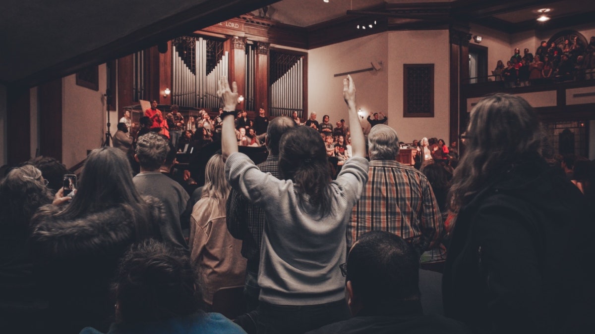 Asbury University chapel service with students raising hands in worship