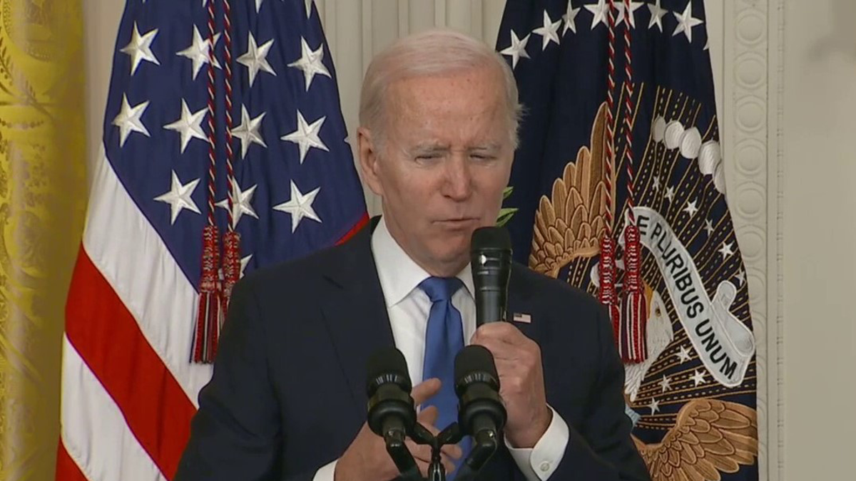 President Biden speaking, US, presidential flags behind him