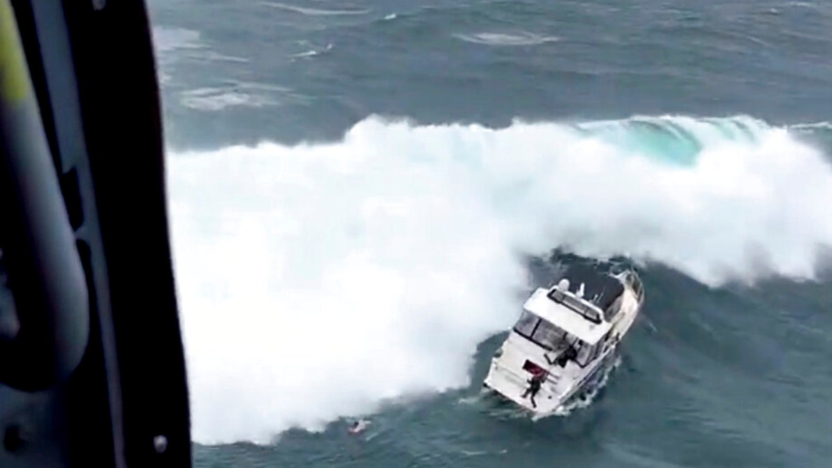 A Coast Guard rescue swimmer reaches a boat