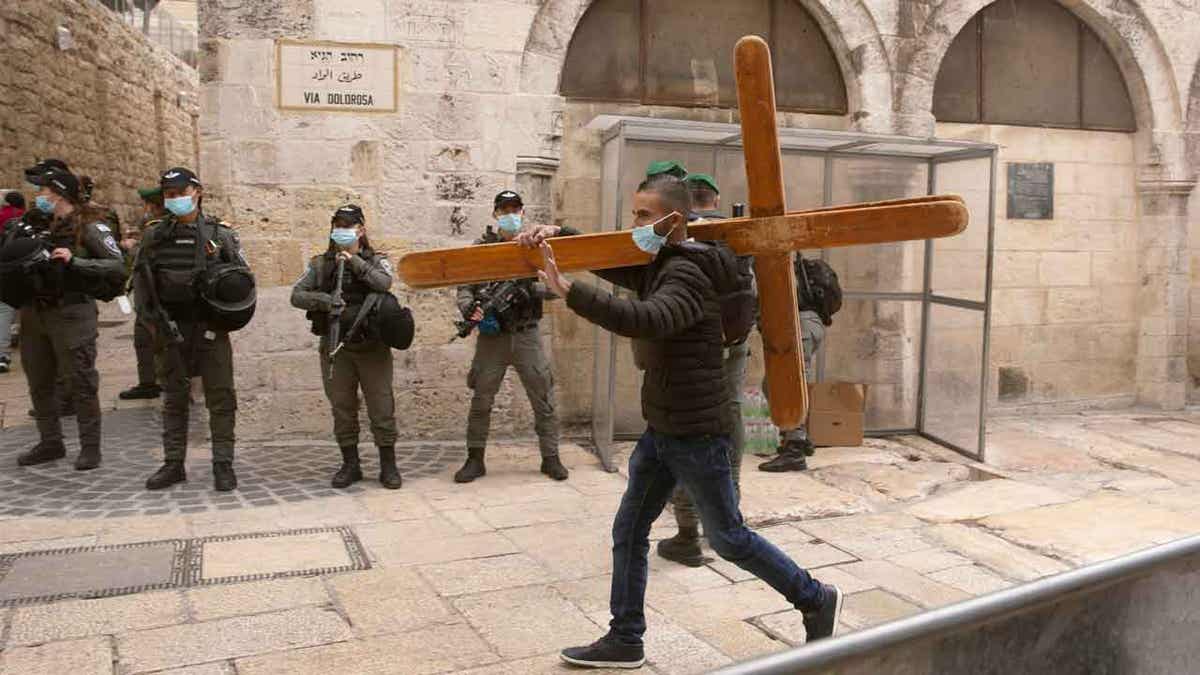 A Christian man carries a cross