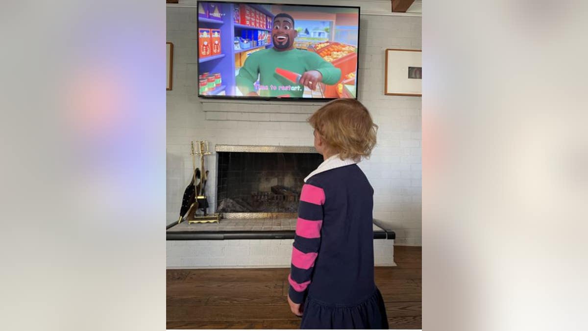 Britt’s 2-year-old daughter stands in rapt attention as the show pushes tofu, spinach and peppers during a grocery store trip. 