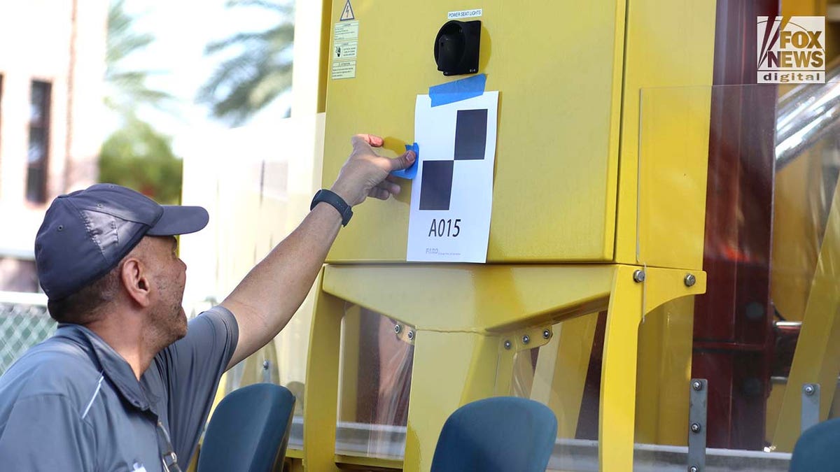 A man tapes a paper marker to a theme park ride.