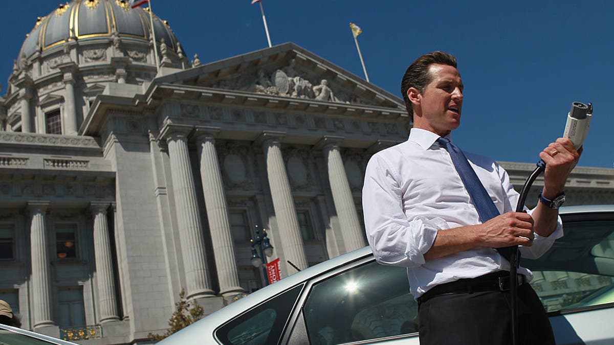 California Gov. Gavin Newsom holds a power cable before test driving a hybrid Toyota Prius when he was mayor of San Francisco.