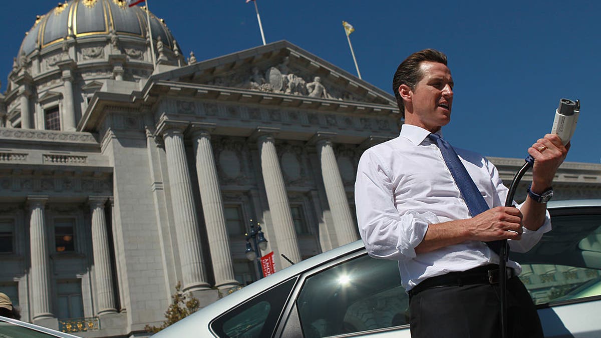 California Gov. Gavin Newsom holds a power cable before test driving a hybrid Toyota Prius when he was mayor of San Francisco.