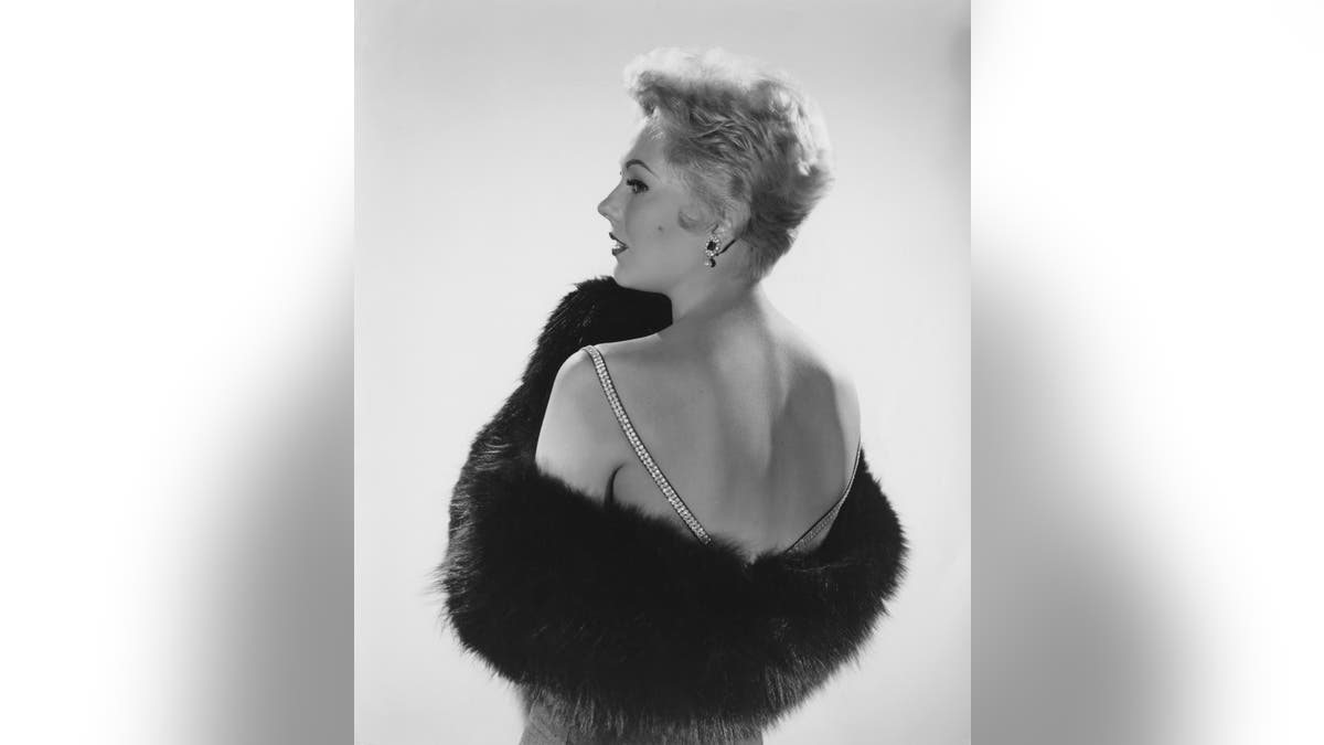 Kim Novak seen from the back wearing a dress and fur wrap
