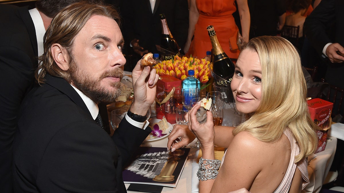 Dax Shepard and Kristen Bell look back at the camera while sitting at a table for the 76th Annual Golden Globe Awards