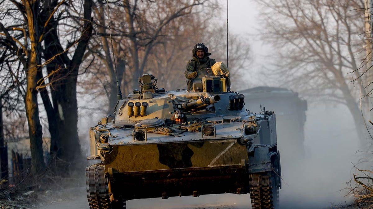 A member of the Russian military rides on a tank.