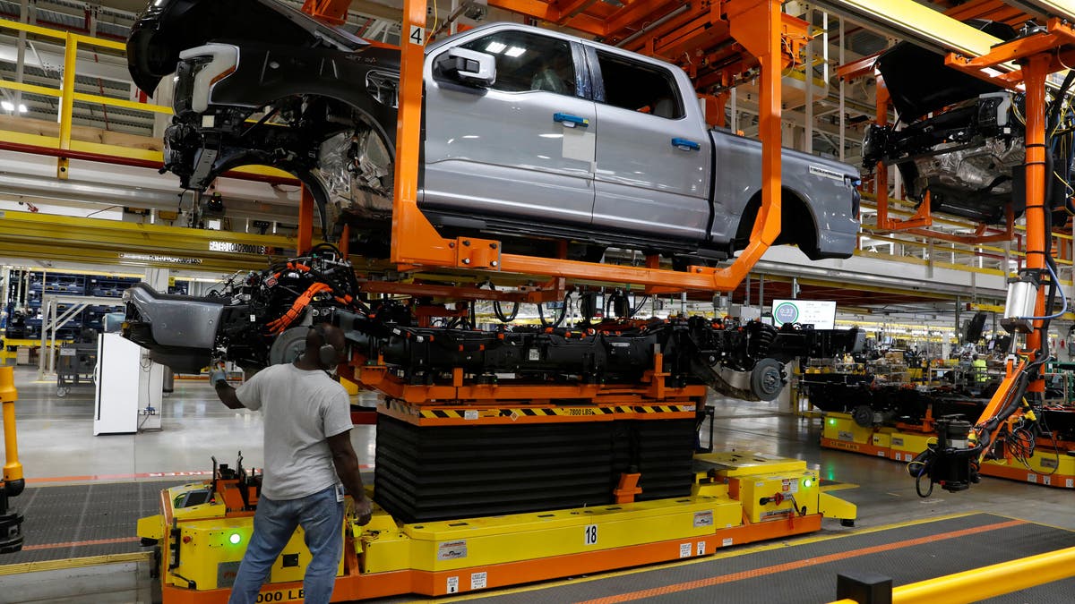 The truck cab is lowered on the frame of Ford Motor Co. battery powered F-150 Lightning trucks under production at their Rouge Electric Vehicle Center in Dearborn, Michigan on September 20, 2022. - Construction crews are back at Dearborn, remaking Ford's century-old industrial complex once again, this time for a post-petroleum era that is finally beginning to feel possible. The manufacturing operation's prime mission in recent times has been to assemble the best-selling F-150, a gasoline-powered vehicle (Photo by JEFF KOWALSKY / AFP) (Photo by JEFF KOWALSKY/AFP via Getty Images)