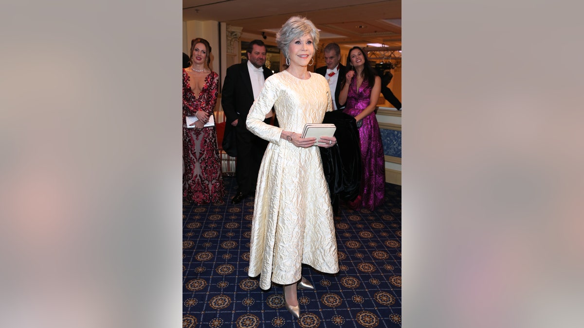 Jane Fonda holding purse in white