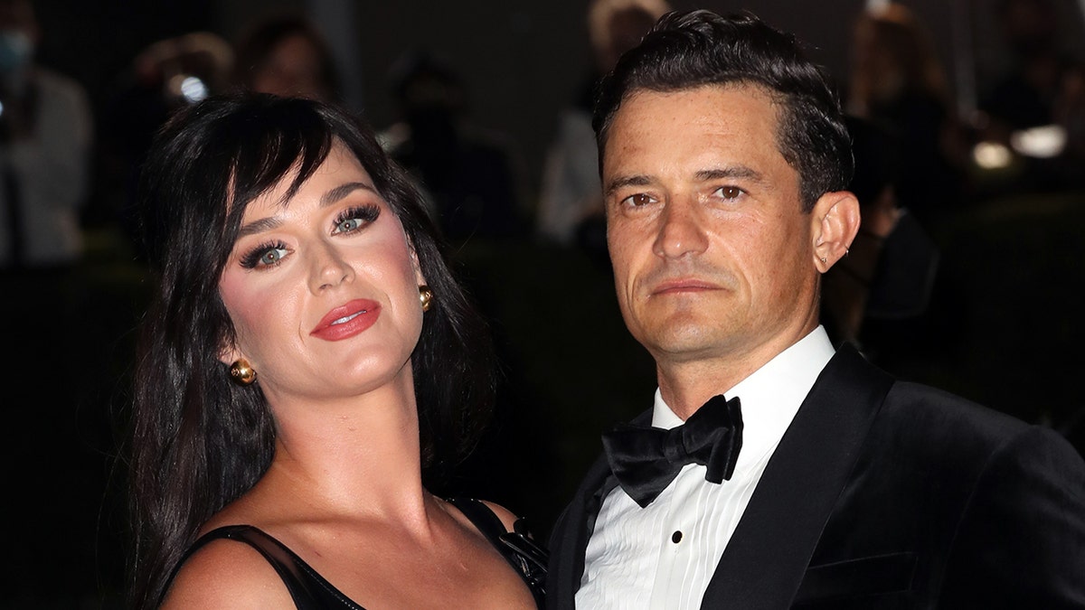 Katy Perry in a black dress with her head tilted back and Orlando Bloom in a black tuxedo at The Academy Museum of Motion Pictures Opening Gala in Los Angeles