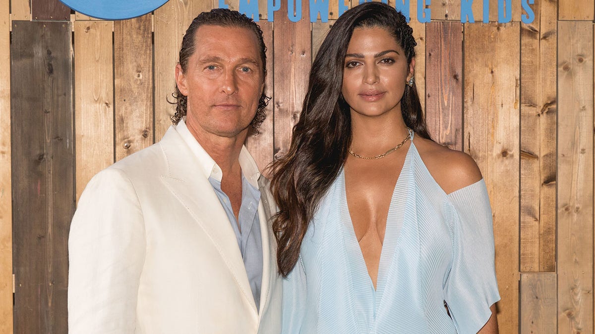 Matthew McConaughey in a white jacket and blue undershirt matches his wife in a light blue plunging dress with cutouts at the shoulders in Austin, Texas