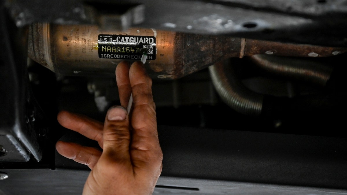 Man places a sticker on a catalytic converter