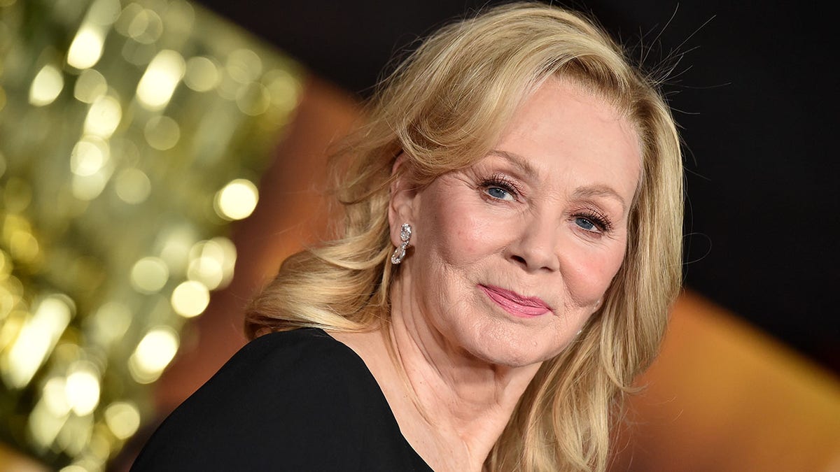Jean Smart with cascading long blonde hair on the red carpet in a black dress for the "Babylon" Global Premiere Screening