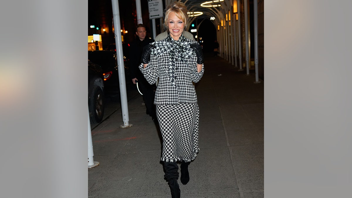 Pamela Anderson walks down the street in black and white hounds tooth jacket with a massive bow on the top