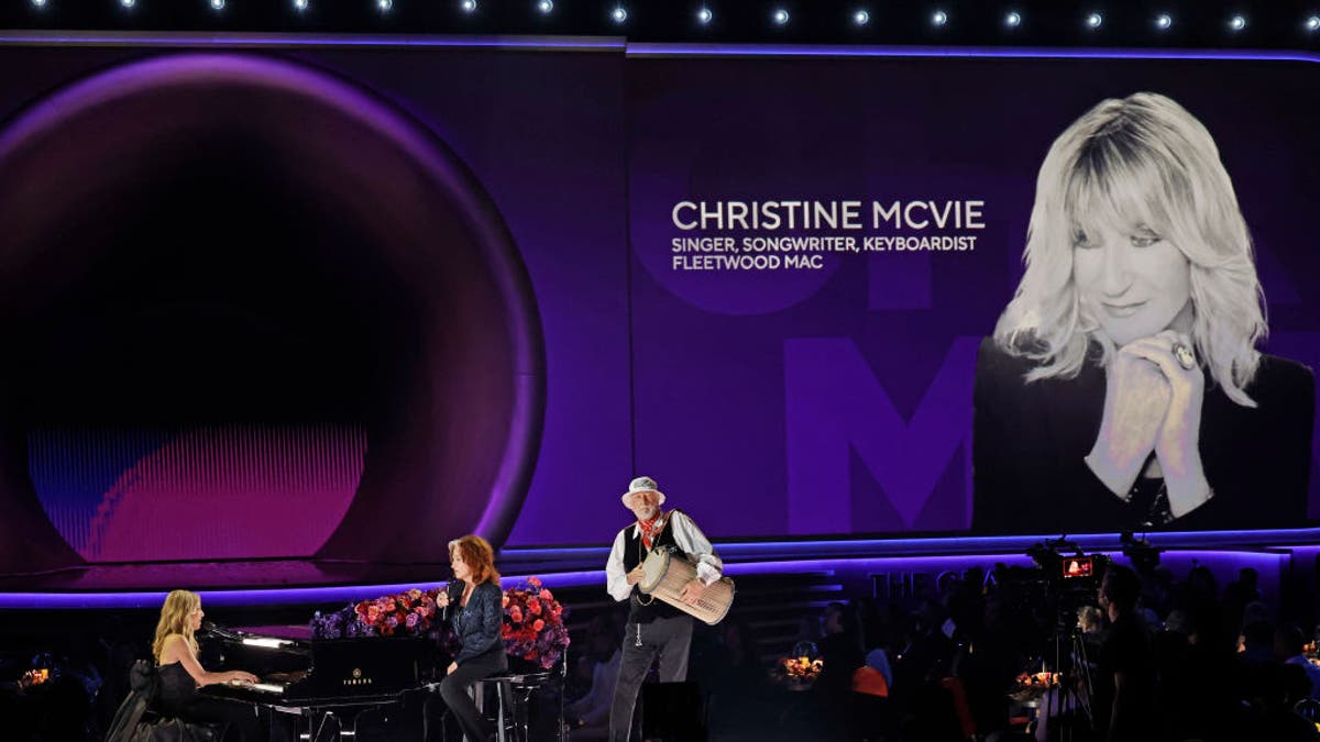 Sheryl Crow, Bonnie Raitt, and Mick Fleetwood perform onstage while an image of the late Christine McVie is displayed during the 65th GRAMMY Awards