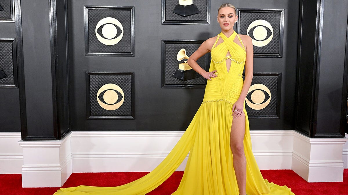 Country star Kelsea Ballerini wears a bright yellow halter gown at the Grammy's with a cut-out towards the middle and slits exposing her legs
