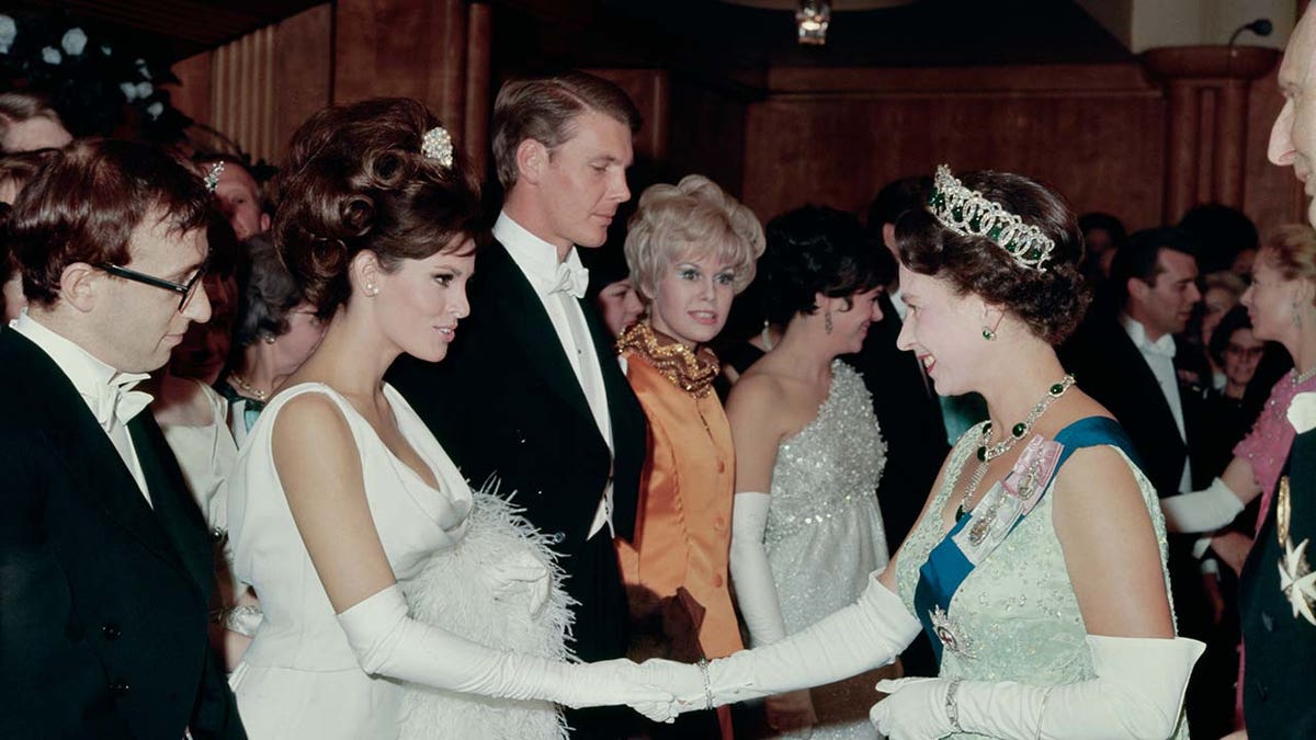 A woman shakes hands with the Queen of England.