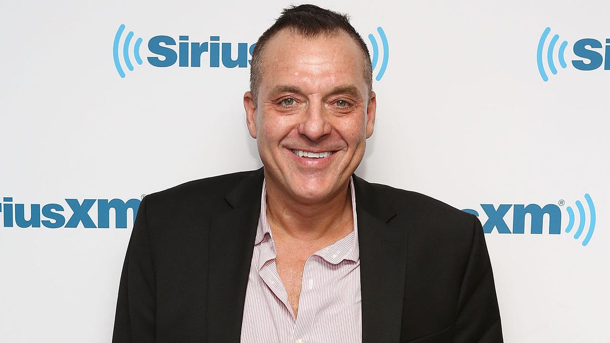 Tom Sizemore smiles in a black jacket and striped shirt on the red carpet