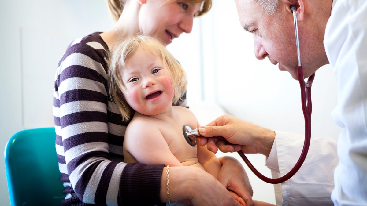 Child with down syndrome is evaluated by a doctor.