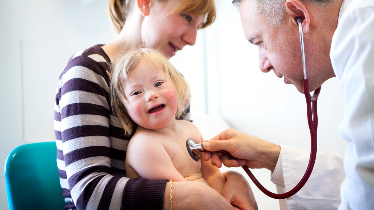 Child with down syndrome is evaluated by a doctor.