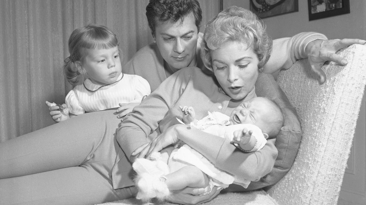 Janet Leigh holding baby Jamie Lee Curtis, as Tony Curtis and Jamie Lee's older sister Kelly look on