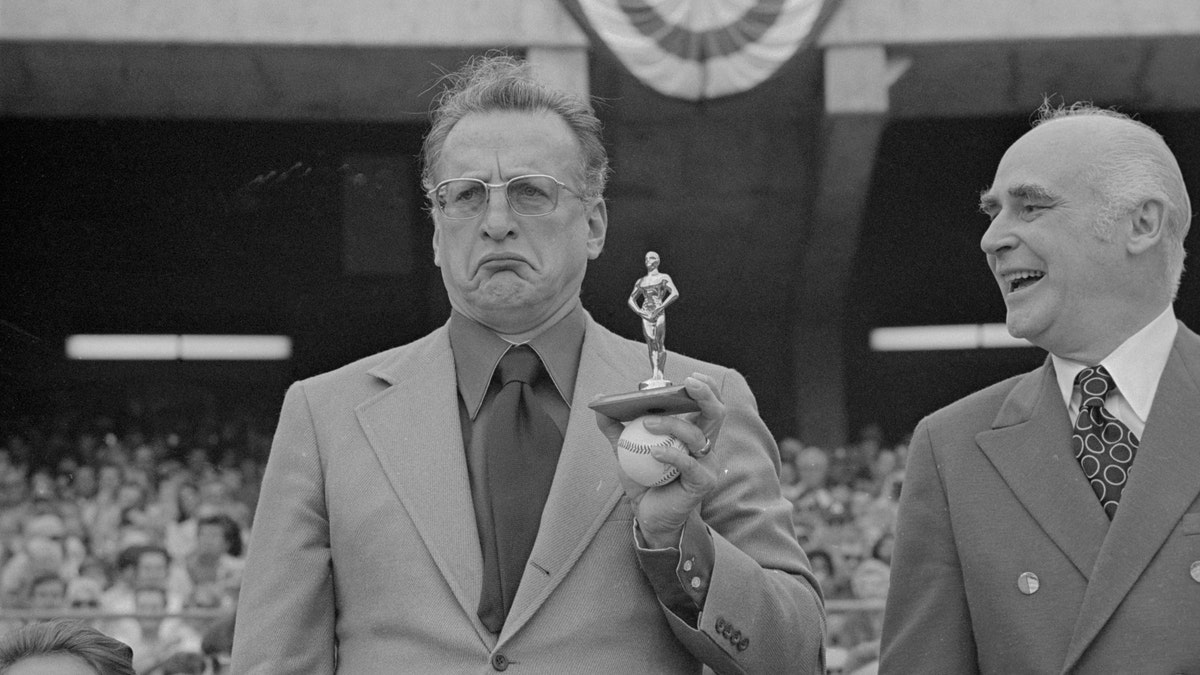 George C. Scott frowning with tiny fake Oscar statue at an event