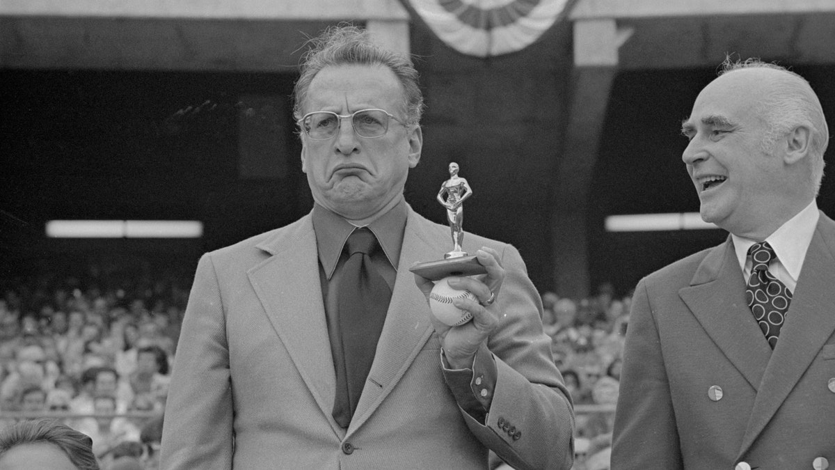 George C. Scott frowning with tiny fake Oscar statue at an event