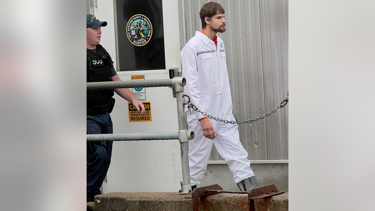 Nathan Carman walks off a Coast Guard vessel in white jumpsuit