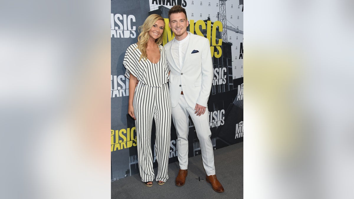 KT Smith in white and black striped jumpsuit with Morgan Wallen in white suit at CMT awards