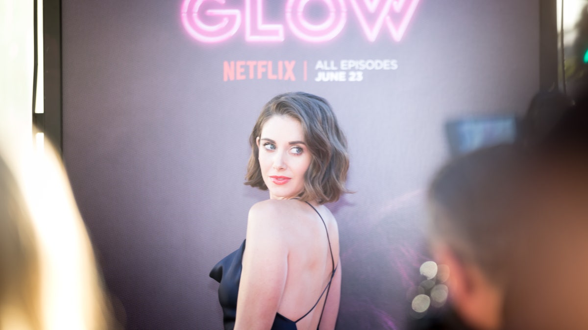 Alison Brie looks over her shoulder at GLOW event