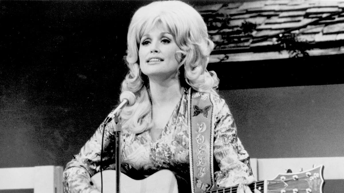 A photo of Dolly Parton playing guitar in 1974.