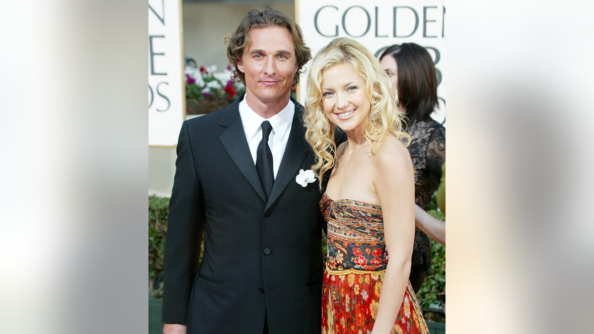 Matthew McConaughey in a black suit and tie for the Golden Globes in 2003 alongside Kate Hudson in a patterned brown, orange, and red dress