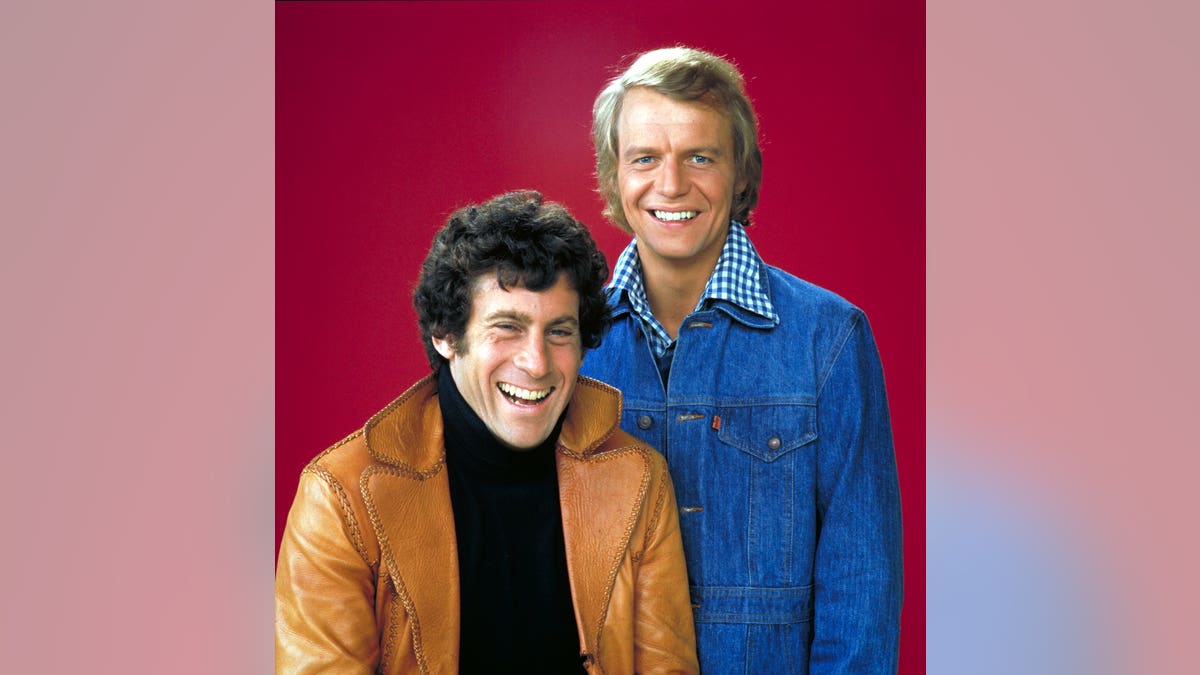 Paul Michael Glaser and David Soul in character as Starsky and Hutch on red background