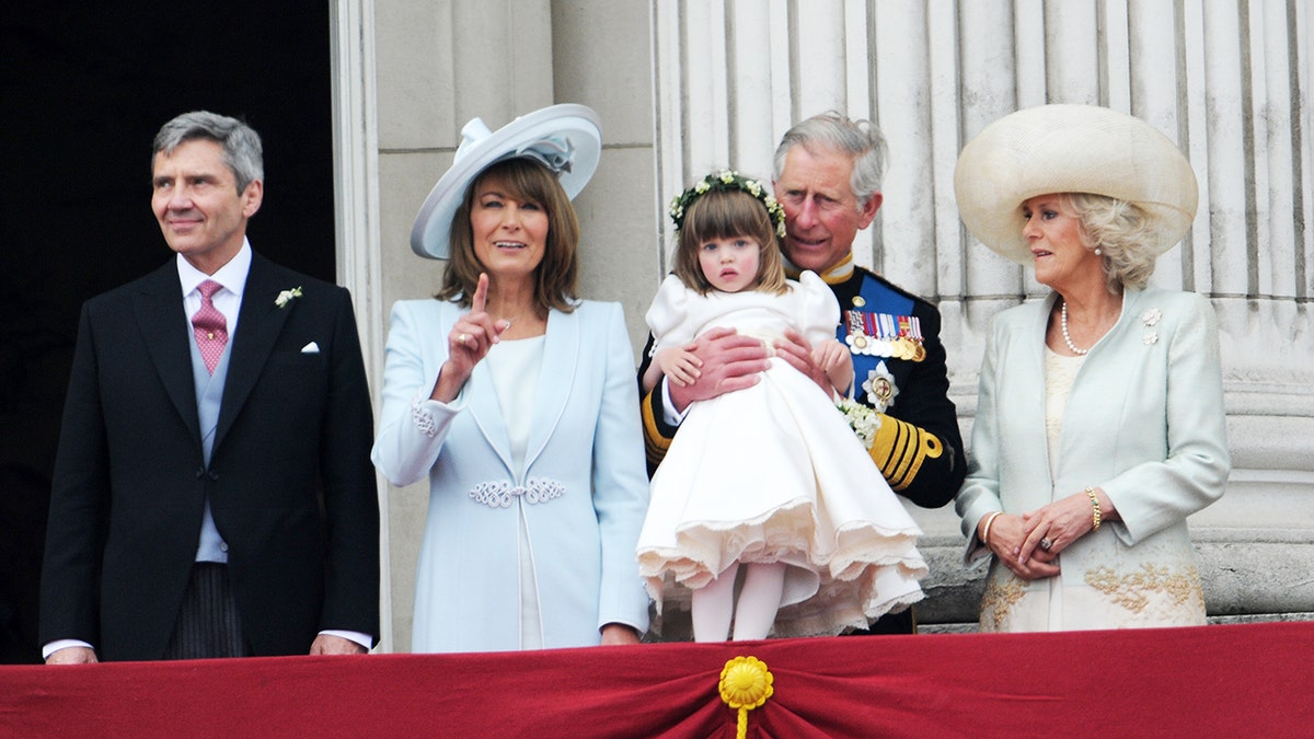 King Charles holding Camilla's granddaughter next to the queen consort and Kate Middleton's parents