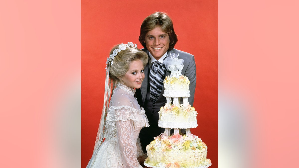Charlene Tilton in character against a red back drop marrying her on-screen boyfriend