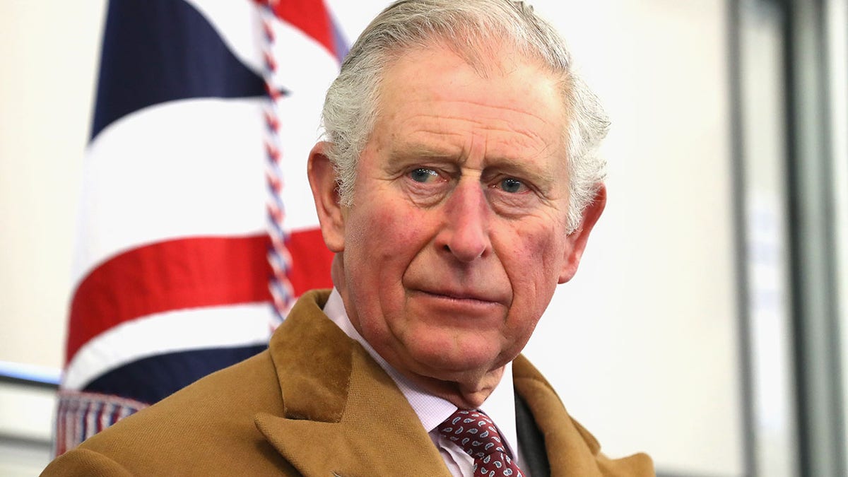 King Charles III looking stern in front of the Union Jack flag