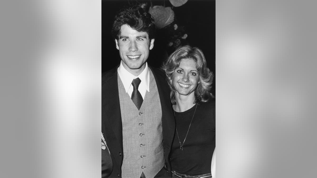 A black and white photo of John Travola and Olivia Newton-John smiling