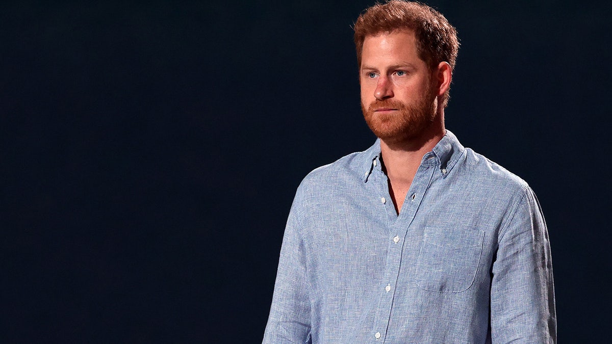 Prince Harry looking serious with a black background