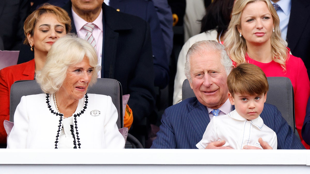 King Charles holding his grandson Prince Louis next to his wife Camilla