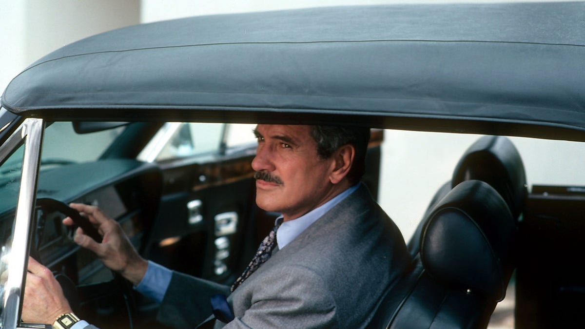 Rock Hudson in the drivers seat of a car in a scene from the television series 'The Devlin Connection'