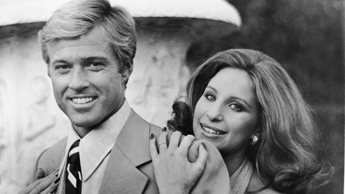 American actress and singer Barbra Streisand hugs American actor Robert Redford from behind in this publicity still from the movie 'The Way We Were'