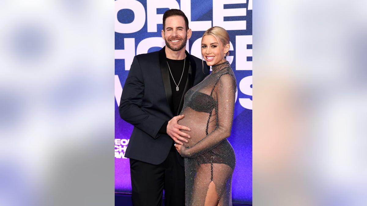 Tarek places his hand on Heather's baby bump on a red carpet