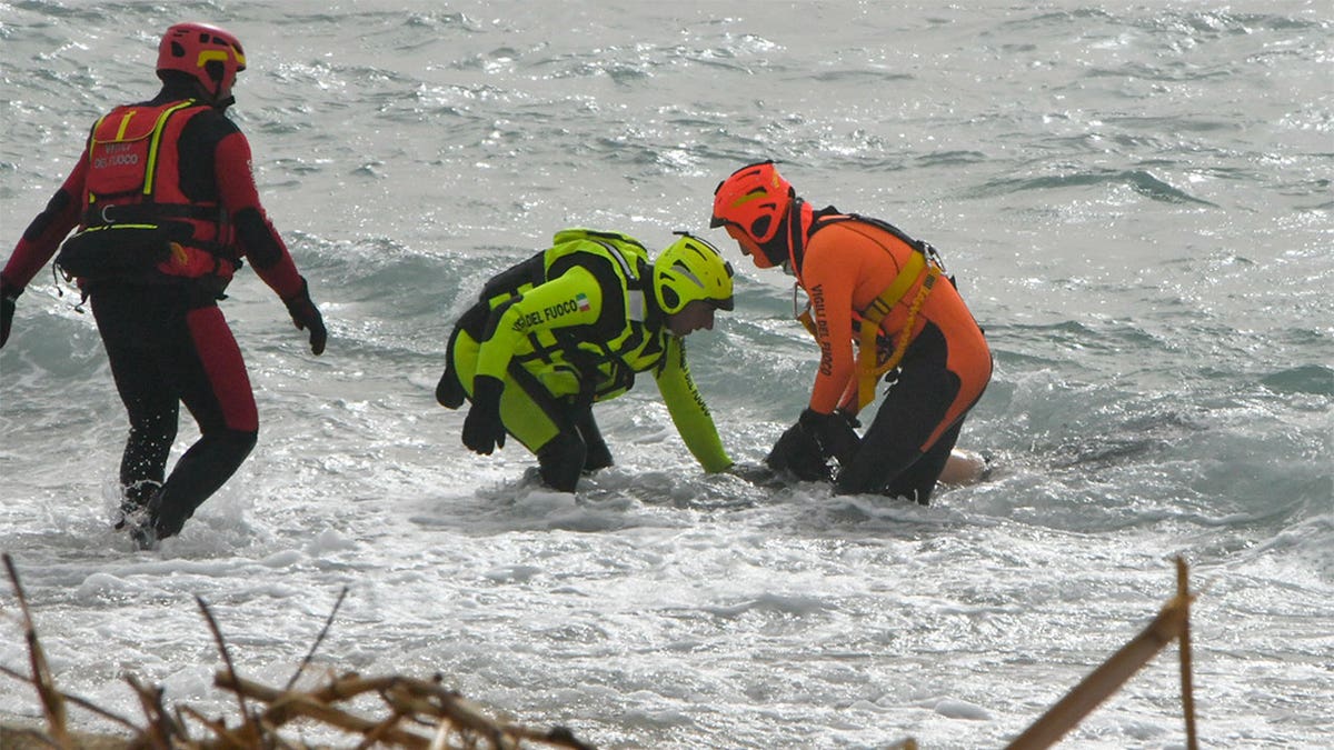 Rescuers pulling a body out from the water.