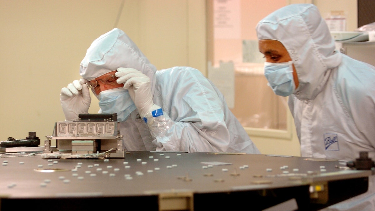 Engineers work on a lens used to correct spherical aberration in a reflecting telescope in NASA's Kepler Mission