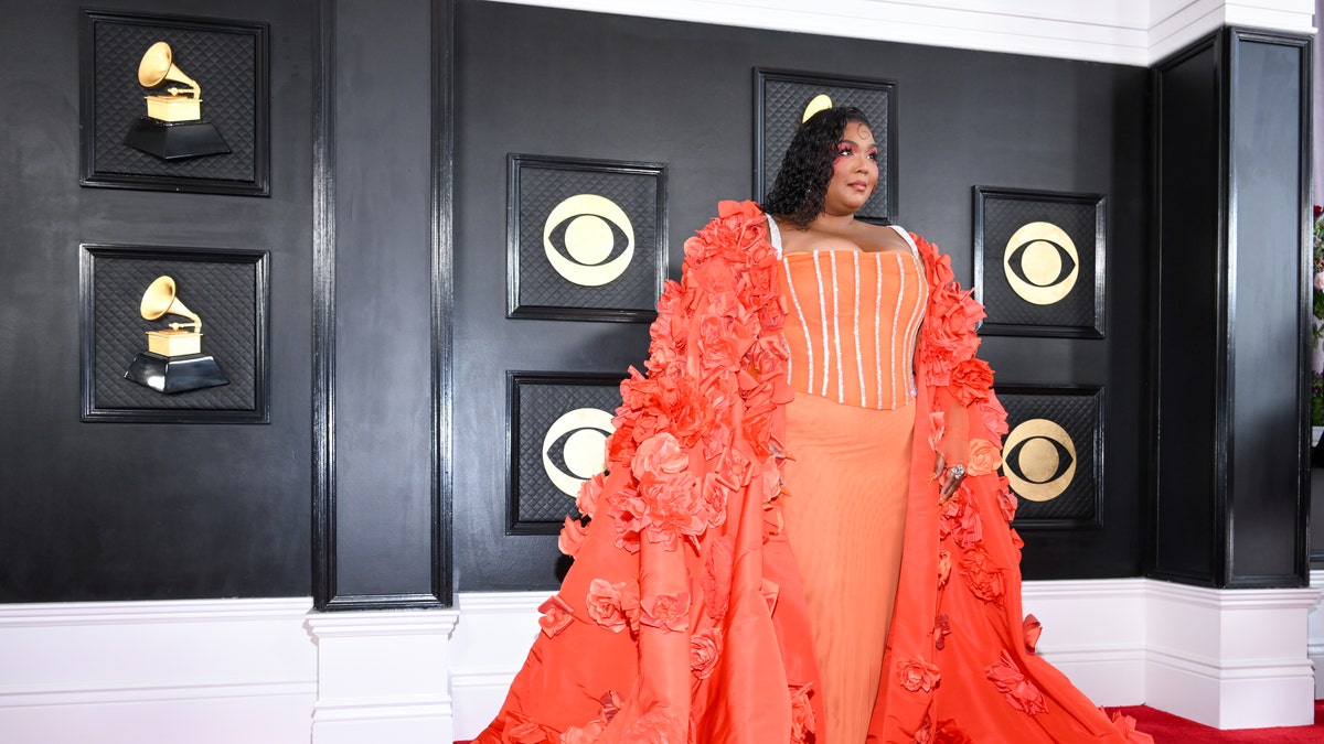 Lizzo in a orange dress and cape at the Grammy Awards