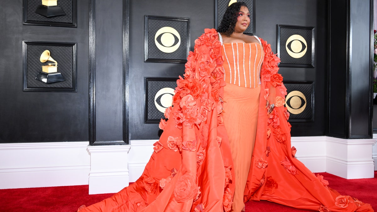 Lizzo in a orange dress and cape at the Grammy Awards