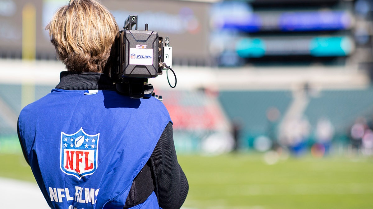 NFL Films cameraman points camera on field