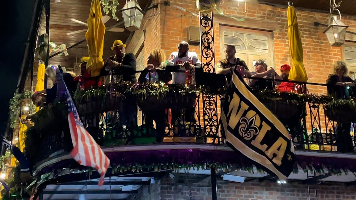 People stand on balcony on Bourbon Street during Mardi Gras