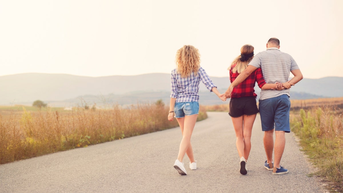 polyamourous 'throuple' walking on road