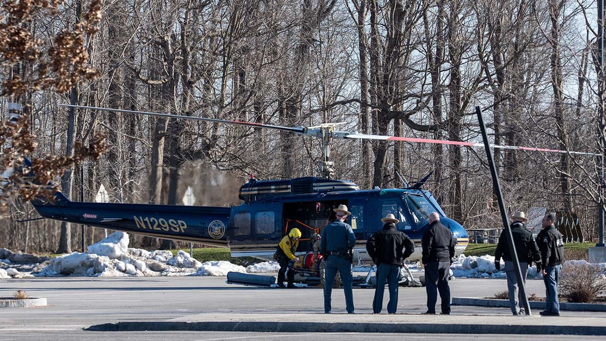 Emergency responders lift a person into a helicopter.